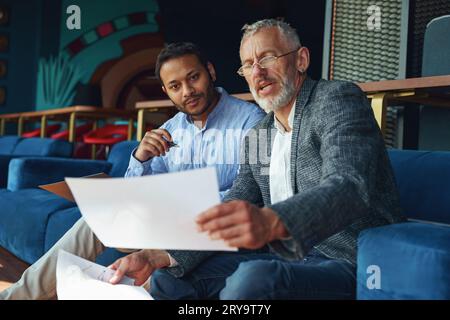 Zwei Kollegen besprechen das Projekt, bevor sie dem Teamleiter im Büro eine Präsentation zeigen Stockfoto