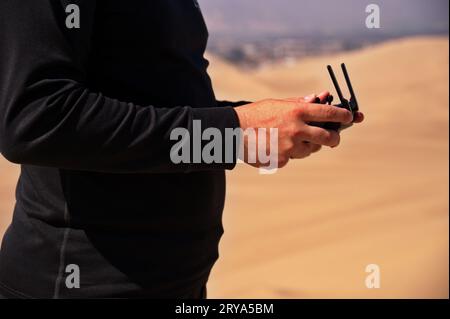 Die Mitte der Hände des Mannes, der die Drohne in der Wüste kontrolliert Stockfoto