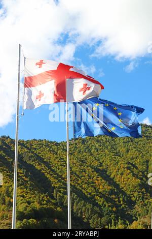 Georgische Flagge und EU-Flagge Schwenkten an sonnigen blauen Himmel Stockfoto