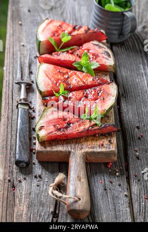Gegrillte Wassermelone mit roter Paprika und Minze. Gegrillte Wassermelone auf Grill mit Flammen. Stockfoto