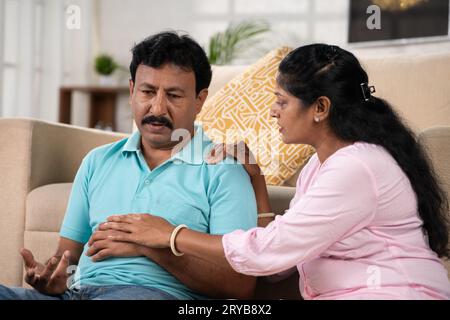 Seitenansicht der indischen Ehefrau, die seinen besorgten Mann tröstet, indem sie zu Hause Vertrauen gibt - Konzept von Zweisamkeit, familiärer Unterstützung und finanziellen Problemen. Stockfoto