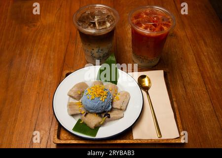 Lokale traditionelle thailändische Dessert süße Mahlzeit und Lebensmittel Fusion Snack Banane in Kokosnussmilch mit Butterfly Pea Eis und Kaffee Tee servieren Kunden essen Stockfoto