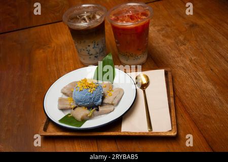Lokale traditionelle thailändische Dessert süße Mahlzeit und Lebensmittel Fusion Snack Banane in Kokosnussmilch mit Butterfly Pea Eis und Kaffee Tee servieren Kunden essen Stockfoto