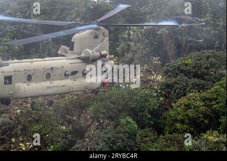 Bezirk Olaon, Panama. 23. September 2023. Ein CH-47 Chinook-Hubschrauber der US-Armee schwebt einige Meter über einer Landezone auf einem abgelegenen Dschungelberg, während das Einsatzpersonal der Panamian am 23. September 2023 im Olaon District, Panama, Ausrüstung lädt. Die US-Streitkräfte halfen bei der Suche und Wiederherstellung eines abgestürzten Servicio Nacional Aeronaval Leonardo AW-139 Hubschraubers, der alle drei an Bord tötete. Kredit: TSgt. Duncan McElroy/USA Air Force/Alamy Live News Stockfoto