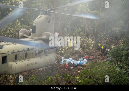 Bezirk Olaon, Panama. 22. September 2023. Ein CH-47 Chinook-Hubschrauber der US-Armee schwebt einige Meter über einer Landezone auf einem abgelegenen Dschungelberg, während das Einsatzpersonal der Panamian am 22. September 2023 im Olaon District, Panama, Ausrüstung lädt. Die US-Streitkräfte halfen bei der Suche und Wiederherstellung eines abgestürzten Servicio Nacional Aeronaval Leonardo AW-139 Hubschraubers, der alle drei an Bord tötete. Kredit: TSgt. Duncan McElroy/USA Air Force/Alamy Live News Stockfoto