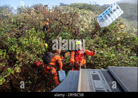 Bezirk Olaon, Panama. 13. September 2023. Panamas Such- und Rettungsspezialisten fangen Vorräte, die vom Rücken eines CH-47 Chinook Hubschraubers der US-Armee geworfen werden, während er einige Meter über einer Landezone auf einem abgelegenen Dschungelberg am 13. September 2023 im Olaon District in Panama schwebt. Die US-Streitkräfte halfen bei der Suche und Wiederherstellung eines abgestürzten Servicio Nacional Aeronaval Leonardo AW-139 Hubschraubers, der alle drei an Bord tötete. Kredit: TSgt. Duncan McElroy/USA Air Force/Alamy Live News Stockfoto