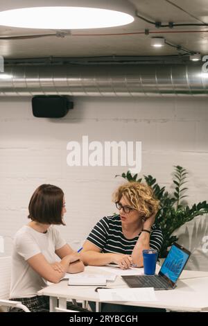 Zwei Frauen diskutieren, planen und sehen sich eine Grafik an, während sie im Büro arbeiten Stockfoto