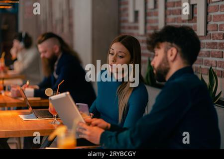 Der Geschäftsmann zeigt seinem Kollegen etwas auf dem Tablet, während er im Café arbeitet Stockfoto