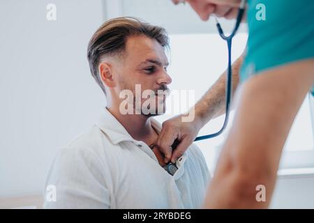 Erfahrener Arzt zur Blutdruckkontrolle des männlichen Patienten im Büro Stockfoto