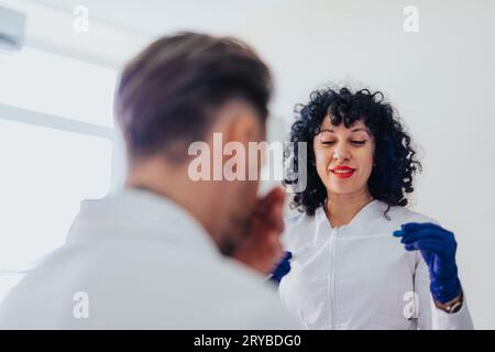 Der Spezialist bietet dem Patienten medizinische Versorgung und Unterstützung im Krankenhauszimmer. Sie kontrolliert den Blutdruck, den Zuckerspiegel und nimmt einen Tupfer. Fachkundiger Arzt sorgt für c Stockfoto