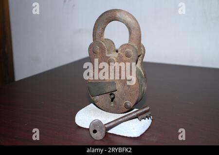 Ein rostiges Vorhängeschloss und Schlüssel auf einem weißen Stein. Stockfoto