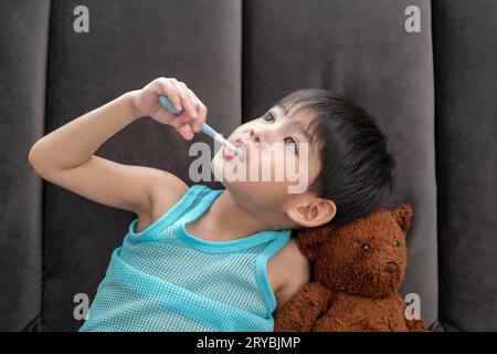 Asiatischer Junge, der seine Zähne im Wohnzimmer putzt Stockfoto