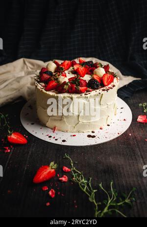 Bild von Pavlova-Kuchen (Desserts) auf rustikalem und dunklem Hintergrund. Food-Fotografie von großen weißen Kuchen (süß) mit Obst zu Geburtstagsfeiern oder anderen Stockfoto