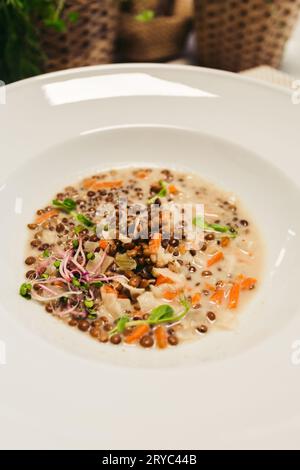 Traditionelle mittelosteuropäische rote Linsensuppe auf weißem Teller auf hölzernem Hintergrund - Blick von oben. Foto von veganer Linsensuppe mit frischem Gemüse. Stockfoto