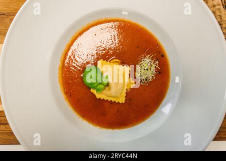 Tomatensuppe oder Gazpacho-Suppe mit Ravioli und Basilikum auf einem rustikalen Holztisch - Blick von oben. Stockfoto