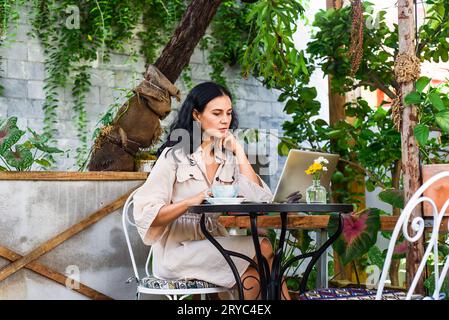 Junge ukrainische brünette Frau, die mit Laptop arbeitet und Kaffee im Café trinkt Stockfoto