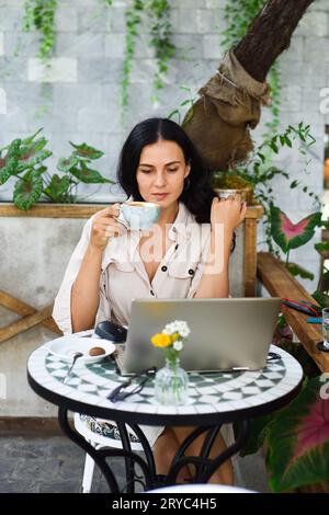 Junge ukrainische brünette Frau, die mit Laptop arbeitet und Kaffee im Café trinkt Stockfoto