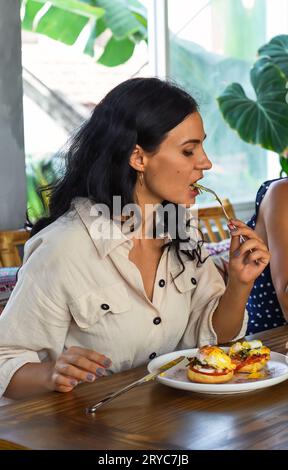 37 Jahre alte ukrainische Frau isst pochierte Eier im Café Stockfoto