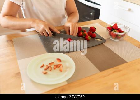 Eine Frau schneidet Erdbeeren mit einem Messer in der Küche Stockfoto