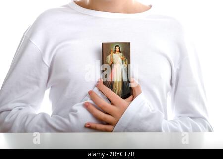 Der kaukasische Junge hält die Ikone des barmherzigen Jesus Stockfoto