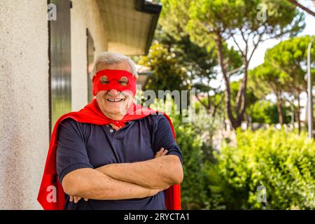 Senior verkleidet als Superheld mit rotem cape und Maske Stockfoto