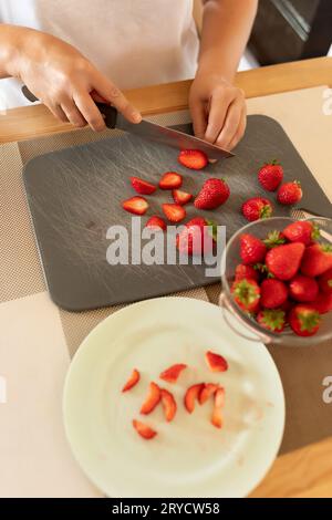 Eine Frau schneidet Erdbeeren mit einem Messer in der Küche Stockfoto