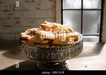 Vor einem mattierten Fenster befinden sich Mandelrhombusse, ein Adventsgebäck aus Shortbread mit einer Schicht geschlagenem Eiweiß. Der rautenförmige Koch Stockfoto