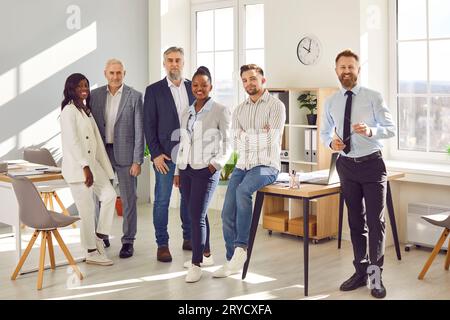 Selbstbewusste lächelnde Geschäftsleute, die im Büro zusammenstehen Stockfoto