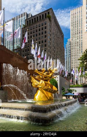 ROCKERFELLER CENTER, NEW YORK, USA, - 15. SEPTEMBER 2023. Eine vertikale Landschaft mit der goldenen Prometheus-Skulptur und dem Brunnen auf der unteren Plaza von Stockfoto