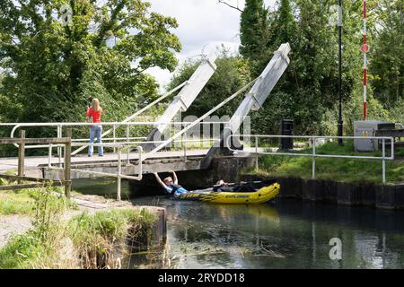 Eine Frau, die über die Warnborough Lift Bridge mit einem Kajak auf dem Basingstoke Canal in der Nähe von Odiham, England, spaziert Stockfoto