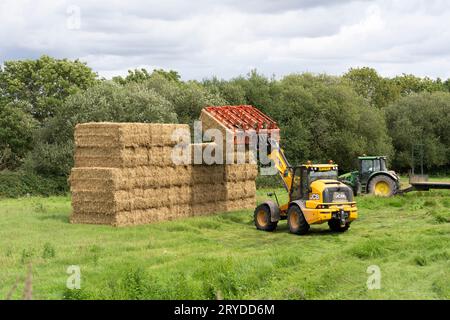Ein britischer Landwirt, der im Herbst Strohballen in einem Hampshire-Feld bei Odiham mit einem Teleskoplader stapelt. UK. Konzept: Brexit Britain / Farming Stockfoto