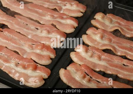 Schließen Sie das Kochen von Speckscheiben auf einem elektrischen Grill Stockfoto