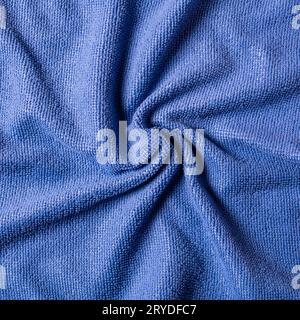 Abstrakter Hintergrund aus zerknittertem weichem Stoff von violetter Farbe, in einer spiralförmigen Nahansicht von oben gedreht. Stockfoto