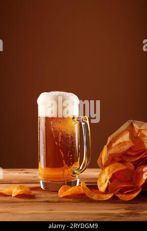 Schließen Sie das Bierglas und die Kartoffelchips über braun Stockfoto