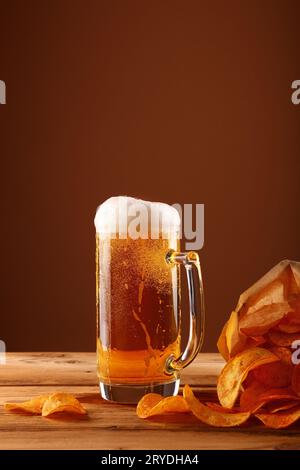 Schließen Sie das Bierglas und die Kartoffelchips über braun Stockfoto