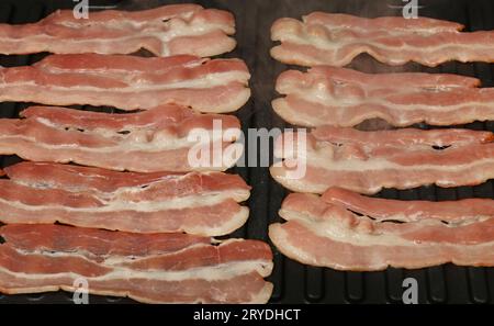 Schließen Sie das Kochen von Speckscheiben auf einem elektrischen Grill Stockfoto