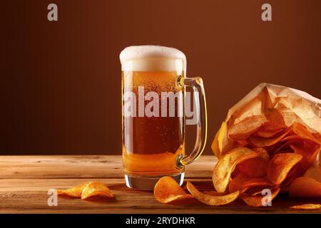 Schließen Sie das Bierglas und die Kartoffelchips über braun Stockfoto