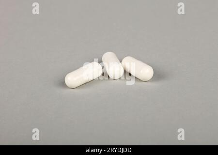 Schließen Sie drei Kapseln mit Gelkappe auf grauem Hintergrund Stockfoto