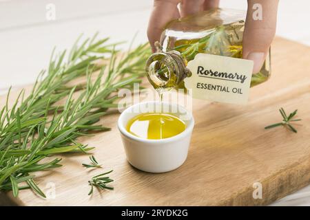 Weibliche Hand, die ätherisches Rosmarin-Öl ausgießt Stockfoto