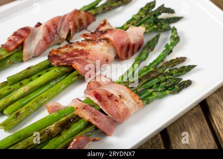 Gekochter Spargel mit gewickeltem Speck auf Teller Stockfoto