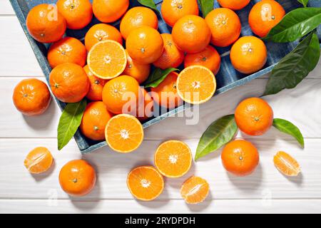 Frische Mandarinenfrüchte mit Blättern auf Holztisch Stockfoto