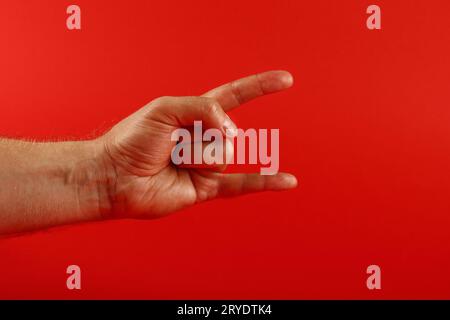 Männerhand mit Teufelshörnern Geste über Rot Stockfoto