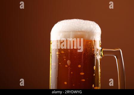 Nahaufnahme Gießen schaumig Bier in Glas über braun Stockfoto