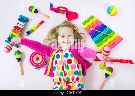 Kind mit Musikinstrumenten. Musikalische Erziehung für Kinder. Buntes Holzspielzeug für Kinder. Kleines Mädchen, das Musik spielt. Junge mit Xylophon, Gitarre Stockfoto