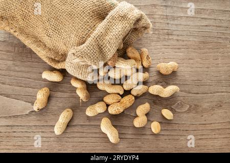 Sacksack und Erdnüsse auf rustikalem Holztisch Stockfoto