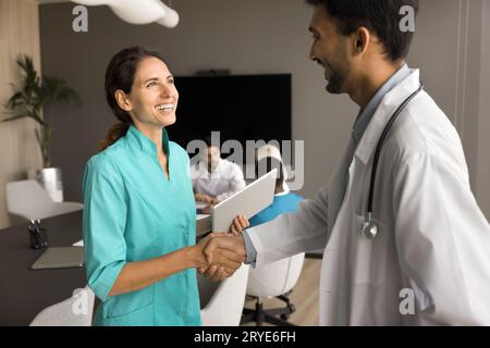 Der Chef des Klinikpersonals gibt dem glücklichen Chirurgen mit Respekt den Handschlag Stockfoto