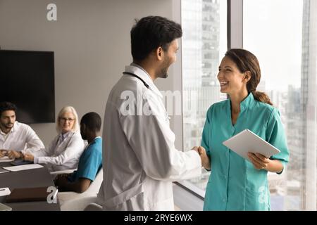 Positive junge Ärztekollegen beim Händeschütteln im Meetingraum Stockfoto