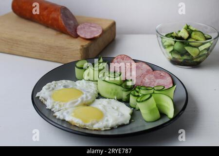 Zastrak-Eier Rühreier Wurst Salat Gurken auf der Trael Blick von der Seite oben. Traditionelles englisches amerikanisches Frühstück. Erste Mahlzeit. Das Benef Stockfoto