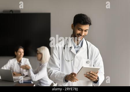 Glücklicher attraktiver indischer Arzt mit Internet-Gesundheitsdienst auf Tablet Stockfoto