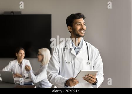 Glücklicher nachdenklicher junger indischer Arzt, der für die Kamera steht Stockfoto